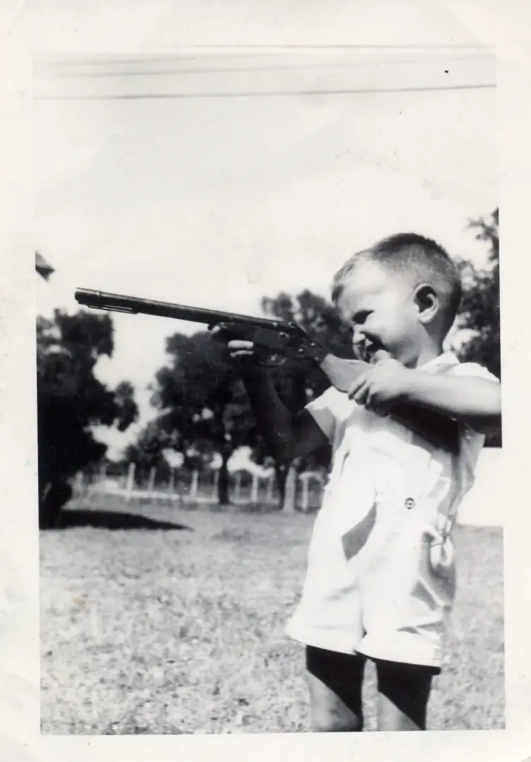 A young boy holding a gun in his hands.